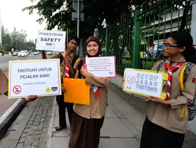 Sejumlah anggota Pramuka yang tergabung dalam Askara melakukan aksi peduli pedestrian di sekitar Jalan Medan Merdeka Timur, Jakarta, Jumat (17/3). Mereka menghimbau pengguna motor untuk tidak melewati trotoar jalan. (Liputan6.com/Helmi Fithriansyah)