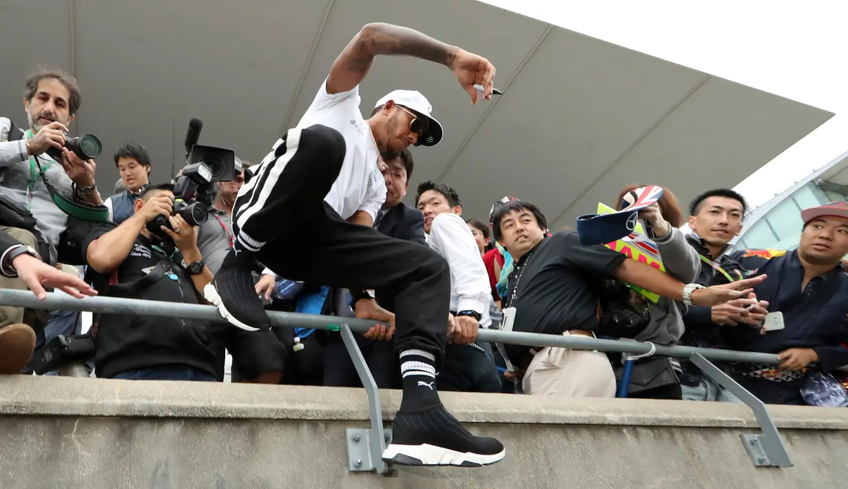 Pembalap Mercedes Lewis Hamilton melompat dari tribun saat jumpa pers jelang Grand Prix F1 di Sirkuit Suzuka, Jepang (5/10). Pada balapan sebelumnya, Hamilton menempati posisi kedua balapan F1 GP Malaysia. (AP Photo/Eugene Hoshiko)