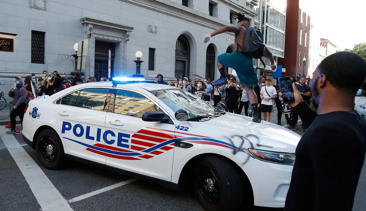 Seorang demonstran merusak mobil polisi saat unjuk rasa di dekat Gedung Putih di Washington (31/5/2020). Demonstran turun ke jalan-jalan di New York City memprotes kematian George Floyd pada (25/5) setelah dijepit di leher oleh seorang petugas kepolisian Minneapolis. (AP Photo/Alex Brandon)