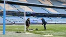 Petugas berjibaku membersihkan salju jelang laga Manchester City melawan PSG pada laga semifinal Liga Champions di Stadion Etihad, Rabu (5/5/2021). (AFP/Paul Ellis)