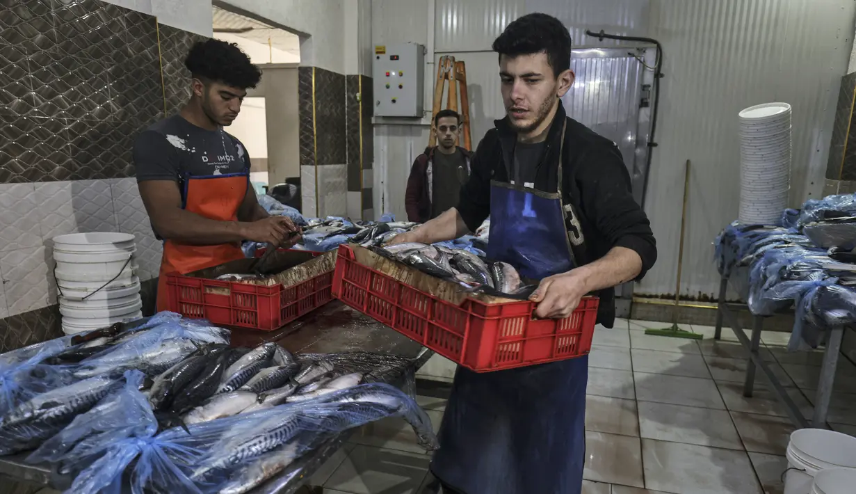 <p>Pemuda Palestina bekerja di fasilitas pengasapan makarel saat ikan itu akan dijual jelang liburan Idul Fitri di Rafah di Jalur Gaza selatan (26/4/2022). Ikan asap makarel menjadi salah satu menu hidangan buka puasa dan Idul Fitri terfavorit bagi warga Gaza selama Ramadhan.(AFP/Said Khatib)</p>