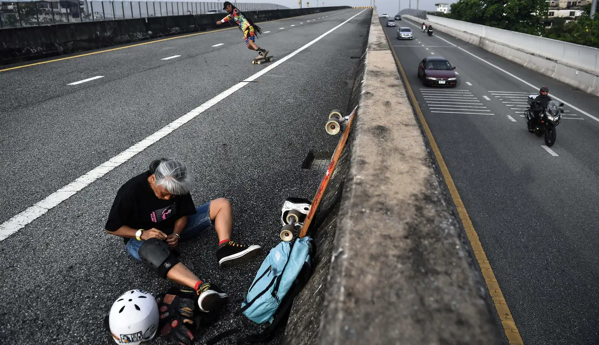 Longboarder dan penderita kanker Nongluck Chairuettichai, juga dikenal sebagai Jeab, mengenakan bantalan lutut saat latihan di Bangkok, 9 September 2020. Melaju di jalan raya yang kosong, kegiatan ini dilakukan sebagai jalan pemulihan dari kanker payudara yang dideritanya. (Lillian SUWANRUMPHA/AFP)