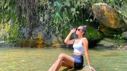 Sambil menikmati keindahan alam di sekitarnya, Garneta Haruni pun berpose dengan santai di area air terjun. Meski santai, gayanya tetap modis dan menawan.  (Liputan6.com/IG/@garnetaharuni).