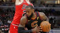 Pebasket Cleveland Cavaliers, LeBron James, berusaha melewati pebasket Chicago Bulls, Lauri Markkanen, pada laga NBA di United Center, Selasa (5/12/2017). Cleveland Cavaliers menang 113-91 atas Chicago Bulls. (AP/Charles Rex Arbogast)