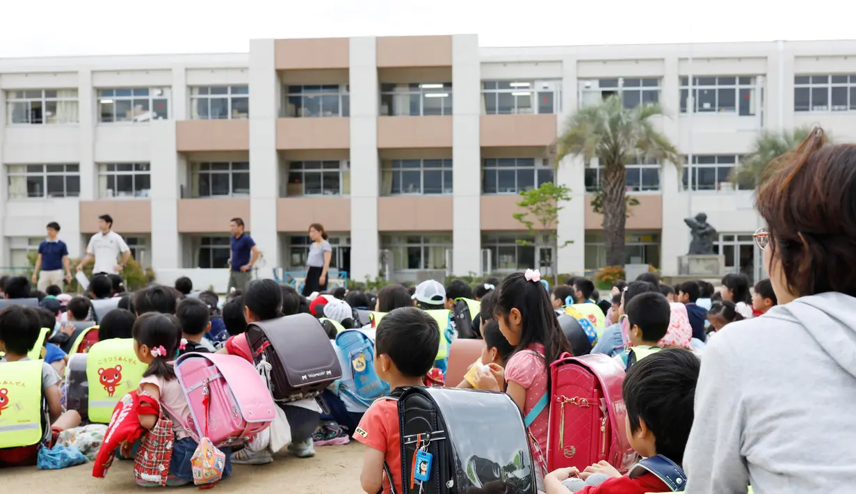Pelajar sekolah berlindung di halaman sekolah di Ikeda, Osaka, Jepang, Senin (18/6). Tidak ada peringatan tsunami yang dikeluarkan terkait gempa bumi yang melanda Osaka. (Takaki Yajima/Kyodo News via AP)
