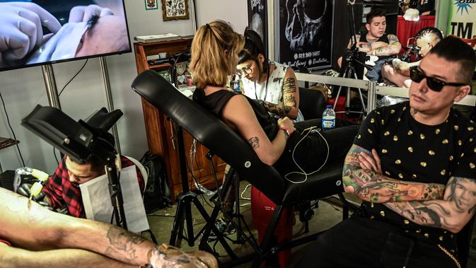 Seniman saat menato sejumlah pencinta tato selama Expotattoo Colombia 2019 di Medellin, departemen Antioquia (2/6/2019). Para penggila tato antusias untuk mentato tubuhnya di festival tato terbesar di negara tersebut. (AFP Photo/Joaquim Sarmiento)
