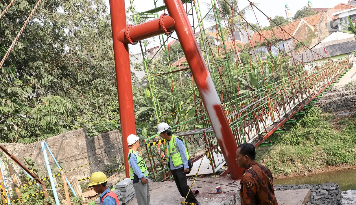 Pekerja menyelesaikan pembangunan jembatan gantung yang diberi julukan Indiana Jones di Srengseng Sawah, Jagakarsa, Jakarta, Jumat (3/8). Pemprov DKI membangun jembatan Indiana Jones karena yang lama sudah tidak layak. (Liputan6.com/Immanuel Antonius)
