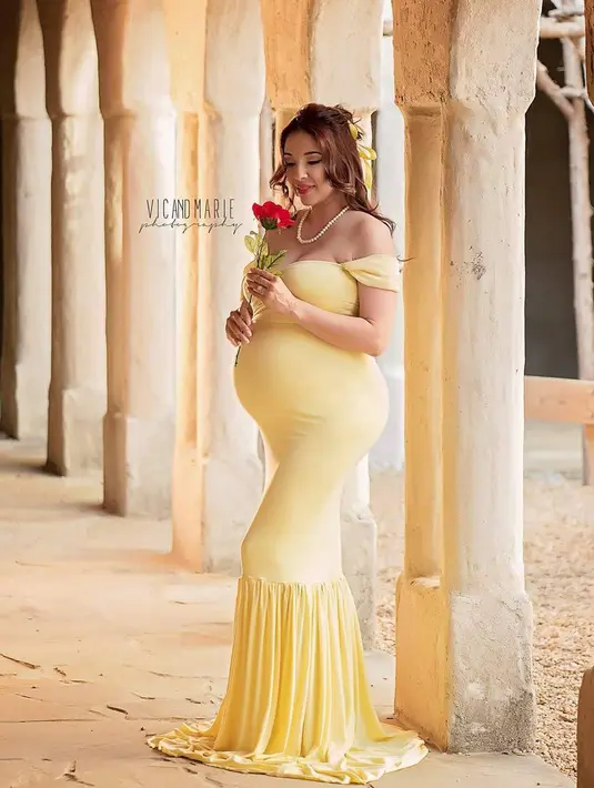 Wanita yang sedang hamil besar ini mengenakan gaun kuning seperti karakter Belle dari film 'Beauty and The Beast'. Dalam konsep pemotretan ini, Vic dan Marie menampilkan para ibu yang sedang hamil besar bak putri Disney. (Instagram/vicandmariephotography)