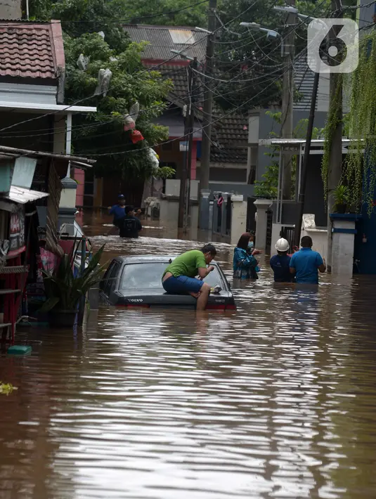 Warga duduk di atas mobil saat banjir merendam jalan dan rumah di RT 003/05, Pejaten, Jakarta, Sabtu ( 20/2/2021). Curah hujan yang tinggi sejak malam hingga dini hari mengakibatkan sejumlah kawasan terendam banjir. (merdeka.com/Imam Buhori)