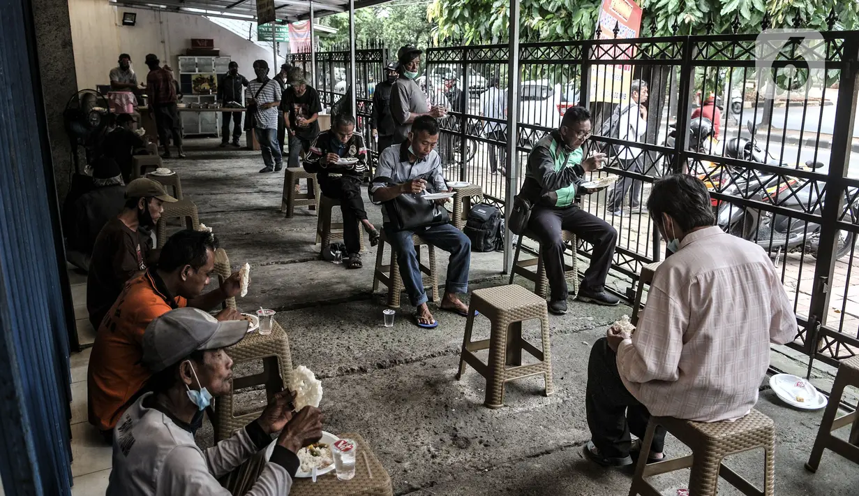 Warga menikmati makan siang gratis di Jalan Basuki Rachmat, Cipinang Muara, Jakarta, Senin (8/3/2021). Sejak Juli 2020, Hadi (40) dibantu teman-temannya menggelar layanan makan gratis kepada warga sebagai bentuk solidaritas dalam menghadapi pandemi Covid-19. (merdeka.com/Iqbal S Nugroho)