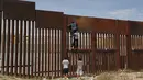 Sejumlah pemuda Meksiko berusaha memanjat tembok besi perbatasan antara Meksiko dan Amerika Serikat di negara bagian Chihuahua, Meksiko (6/4). Mereka menyeberang secara ilegal ke Sunland Park dari Ciudad Juarez. (AFP/Herika Matinez)
