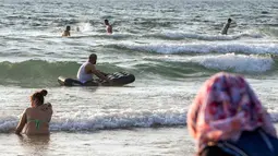 Sejumlah muslim bermain ombak saat menikmati libur lebaran di pantai laut Mediterania di Tel Aviv, Israel, 26 Jni 2017. (AFP PHOTO / JACK GUEZ)