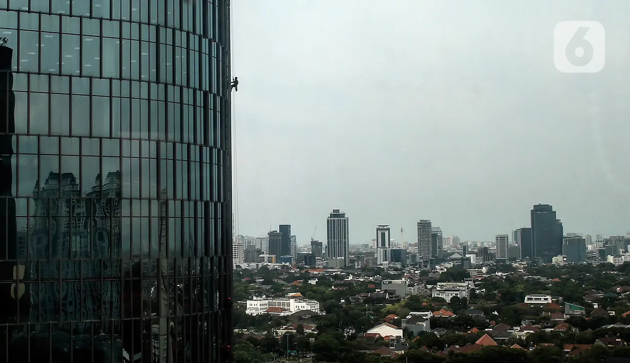 Pekerja saat membersihkan kaca gedung bertingkat di kawasan Kuningan, Jakarta, Minggu (19/12/2021). Pekerja ini harus bergelantungan dengan seutas tali untuk membersihkan dinding-dinding gedung bertingkat yang tingginya kurang lebih mencapai 150 meter. (Liputan6.com/Johan Tallo)