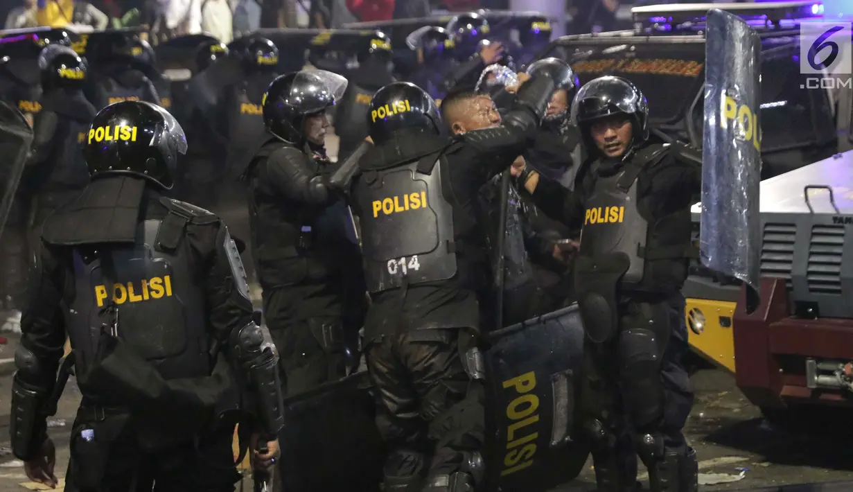 Personil Kepolisian dari satuan Brimob beristirahat sambil minum di sela-sela menghalau massa yang berlaku anarkis di sekitar depan Gedung Bawaslu, Jalan MH Thamrin, Jakarta, Rabu (22/5/2019). Aksi unjuk rasa yang dimotori GNKR berakhir ricuh. (Liputan6.com/HelmiFithriansyah)