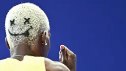 Rambut pelari Jamaika, Janieve Russell bergambar emoji wajah tersenyum saat berkompetisi dalam nomor lari gawang 400 meter Olimpiade Paris 2024 di Stade de France, Paris, Prancis, 6 Agustus 2024. (AFP/Jewel Samad)