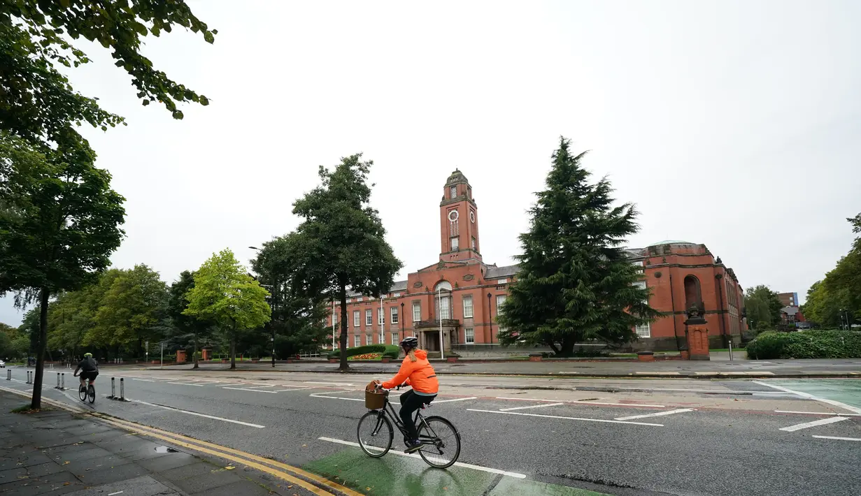 Seorang pesepeda melintas di Trafford Town Hall, Greater Manchester, Inggris (2/9/2020). Menurut BBC, sejumlah wilayah di Greater Manchester tidak akan melonggarkan pembatasan lockdown sesuai rencana awal karena pemerintah membatalkannya. (Xinhua/Jon Super)