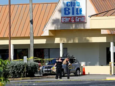 Petugas polisi berjalan di tempat parkir Club Blu setelah insiden penembakan di Fort Myers, Florida, Senin (25/7). Dua orang tewas dalam serangan penembakan di klub malam tersebut yang dilaporkan sebagai tempat pesta untuk remaja. (REUTERS/Joe Skipper)