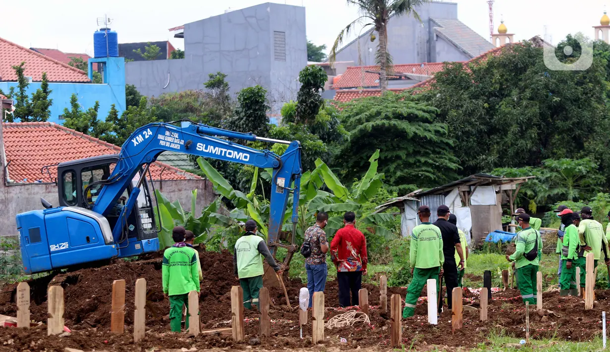Aktivitas alat berat jenis eksavator membantu proses penggalian makam jenazah dengan protokol COVID-19 di area khusus TPU Srengseng Sawah, Jakarta, Kamis (14/1/2021). Pada Selasa (12/1) lalu, 47 jenazah dimakamkan dengan protokol COVID-19 di TPU Srengseng Sawah. (Liputan6.com/Helmi Fithriansyah)
