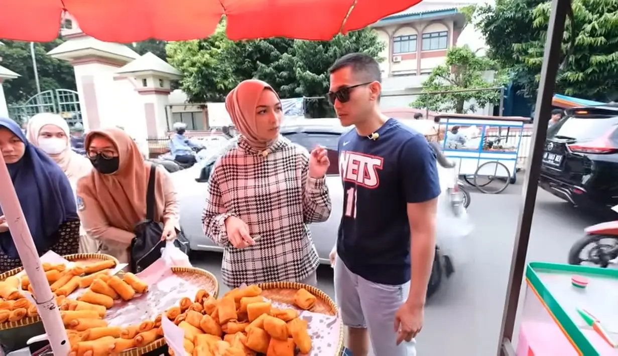 Setelah berhenti di salah satu kampus, tampak banyak pedagang yang menjual takjil. Setelah memarkirkan motor, keduanya melihat-lihat takjil.  [Youtube/Ciky Citra Rezky]