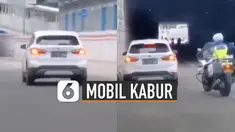 Terlihat mobil putih melintas dengan kecepatan tinggi dan di belakangnya ada anggota polisi yang mengejarnya dengan motor.