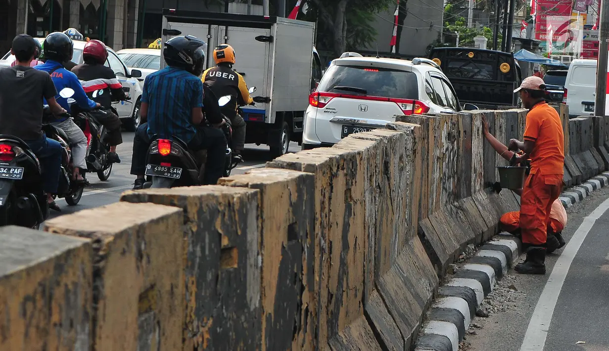 Kendaraan melintas saat anggota PPSU melakukan pengecatan trotoar di Kawasan Jakarta, Selasa (1/8). Selain untuk memperindah Ibu Kota Jakarta, pengecatan tersebut dilakukan untuk menyambut Hari Kemerdekaan RI ke-72. (Liputan6.com/Helmi Afandi)