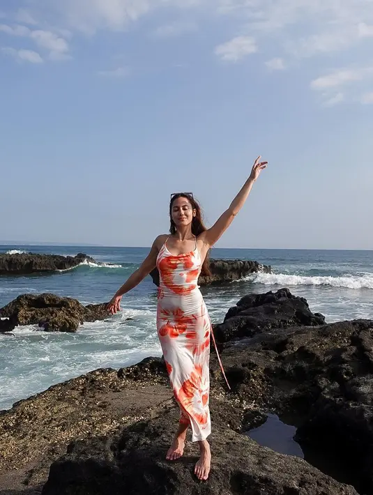 Tie dye bodycon dress warna putih dengan sentuhan rona oranye bak sunset membuat penampilan Pevita Pearce memesona saat berpose di pantai.  [Foto: IG/pevpearce].