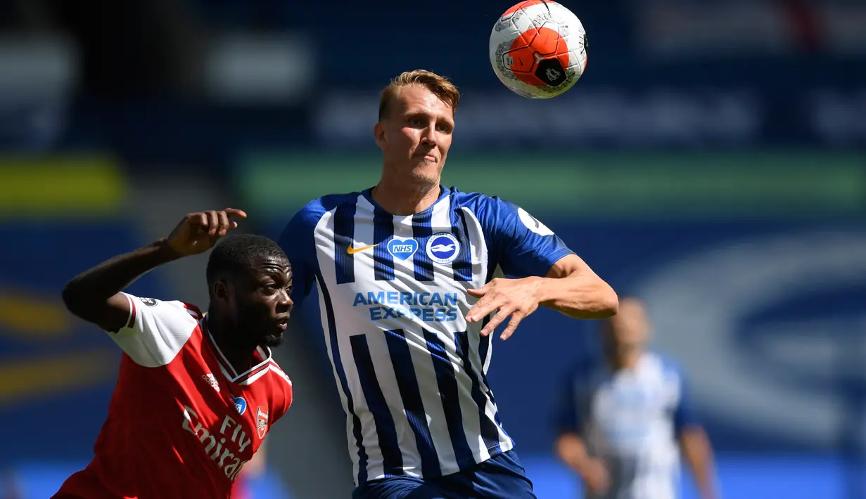 Winger Arsenal, Nicolas Pepe berusaha berebut bola dengan pemain Brighton & Hove Albion, Dan Burn pada lanjutan pertandingan Liga Inggris di The American Express Community Stadium, Sabtu (20/6/2020). Sempat unggu lebih dahulu, Arsenal justru tumbang 1-2 di tangan Brighton. (Mike Hewitt/Pool via AP)