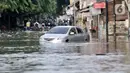 Sebuah mobil terjebak banjir di Jalan RA Kartini, Bekasi, Jawa Barat, Kamis (2/1/2020). Banjir yang merendam Jalan RA Kartini sejak kemarin melumpuhkan akses kendaraan dan perekonomian warga setempat. (merdeka.com/Iqbal Nugroho)