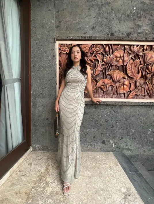 Kondangan ala Hesti yang berhasil pamer body goals. Ia mengenakan sebuah dress tanpa lengan bernuansa silver dengan detail halter-neck yang cantik. [Foto: Instagram/hestipurwadinata]