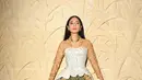 Dian Sastrowardoyo tampil memukau dengan kebaya kutubaru bermotif kembang berwarna cokelat muda, dipadukan dengan bustier top putih berstruktur lengkap dengan detail potongan unik di bagian bawah yang membentuk siluet peplum. Kebaya tersebut kemudian dipadukan dengan kain batik lilit berwarna hijau-putih bermotif geometris dan floral yang khas, menghadirkan harmoni antara tradisi dan gaya kontemporer. [@hagaipakan]