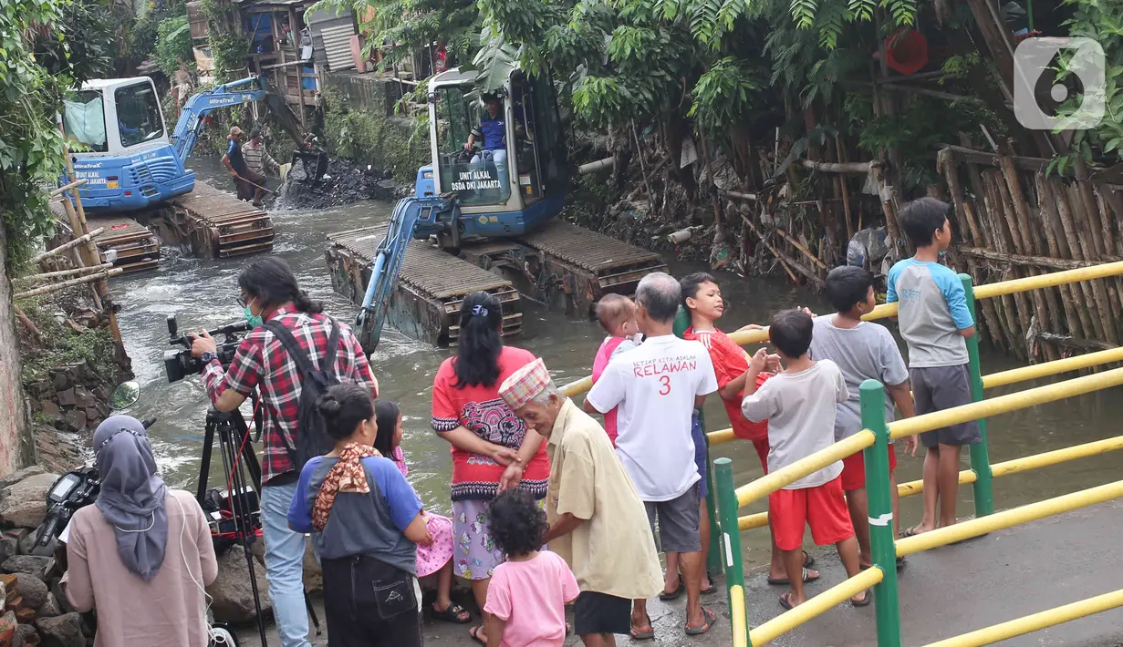 Warga mengamati alat berat yang dioperasikan untuk pengerukan Kali Mampang, Pondok Jaya, Sabtu (19/2/2022). Putusan Majelis Hakim Pengadilan Tata Usaha Negara (PTUN) Jakarta menghukum Anies Baswedan untuk mengeruk Kali Mampang secara tuntas hingga wiilayah Pondok Jaya. (Liputan6.com/Herman Zakharia)