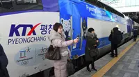 Perempuan selfie di depan kereta cepat yang membawa ke lokasi olimpiade musim dingin korea selatan (JUNG YEON-JE / AFP)