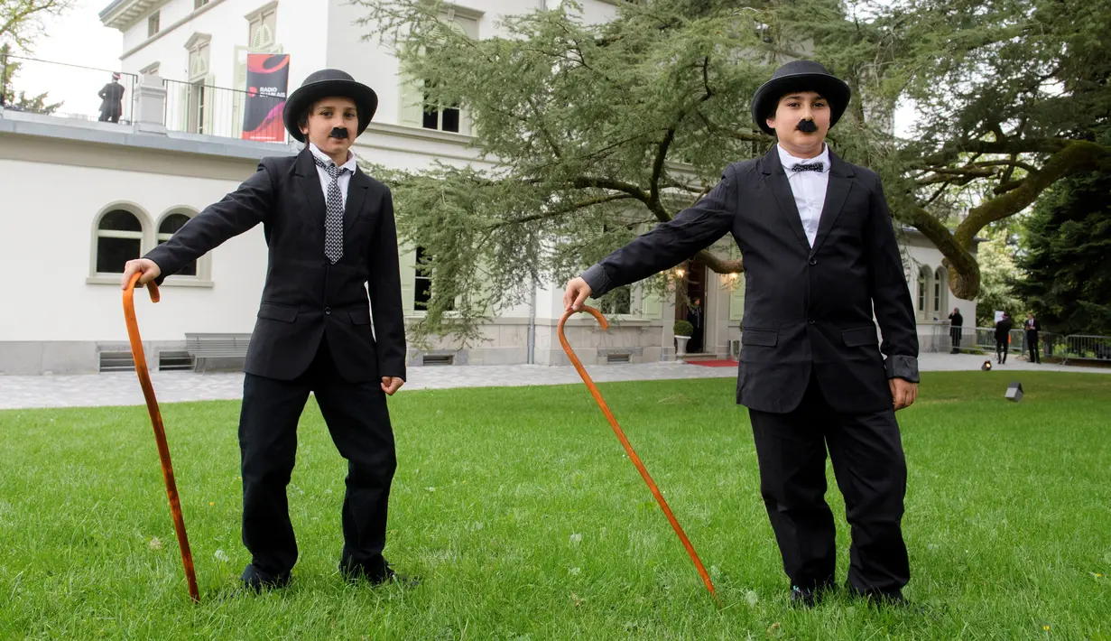 Penggemar berpakaian mirip Charlie Chaplin berpose saat menggelar pertemuan di Corsier sur Vevey, Swiss, Minggu (16/4). Sebanyak 662 orang menirukan gaya Charlie Chaplin lengkap dengan topi, kumis kotak, dan tongkat kayu.  (Richard Juilliart/AFP)