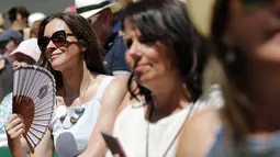 Seorang fans wanita menggunakan kipas saat menyaksikan pertandingan tenis pada hari ketiga Kejuaraan Wimbledon 2017 di The All England Lawn Tennis Club di Wimbledon, London barat daya, Inggris (5/7). (AFP Photo/Adrian Dennis)