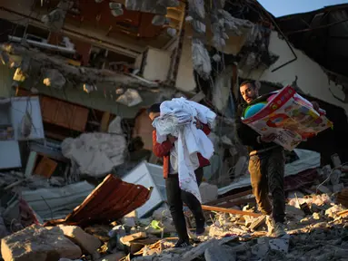 Warga memindahkan barang-barang dari rumah mereka yang hancur setelah gempa di Samandag, Turki, 16 Februari 2023. Otoritas Turki mengatakan setidaknya 38.044 orang telah tewas, sementara pemerintah Suriah dan PBB mengatakan lebih dari 5.800 orang tewas di sana. (AP Photo/Francisco Seco)