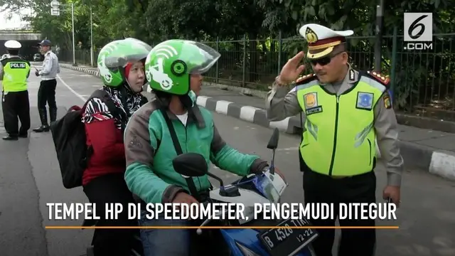 Petugas polisi Polres Jakarta Timur menegur sejumlah pengemudi ojek online yang menggunakan HP saat berkendara. Petugas mengimbau pengemudi ojek online untuk tidak menaruh HP di speedometer atau stang pada kendaraan.