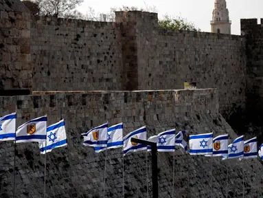 Bendera Israel berkibar di depan benteng-benteng di dekat Gerbang Jaffa di Kota Tua Yerusalem (20/3). Gerbang Jaffa adalah sebuah portal yang dibuat dari batu yang berada dalam deret tembok bersejarah Kota Lama Yerusalem. (AFP Photo/Thomas Coex)