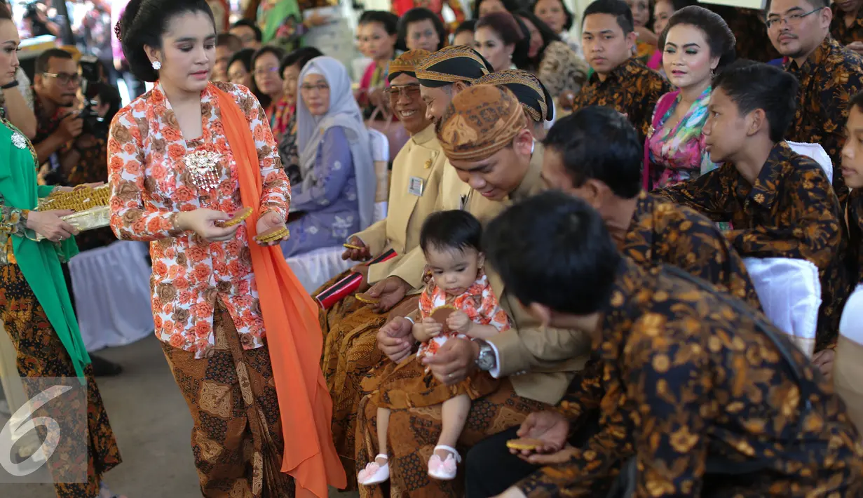 Anggota keluarga Selvi Ananda membagikan kreweng kepada tamu undangan pada prosesi sade dawet (jual dawet) di depan rumah kontrakan mempelai wanita di Jalan Kutai Raya, Banjarsari, Solo, Jateng, Rabu (10/6/2015). (Liputan6.com/Faizal Fanani)