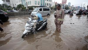 Seorang pengendara memperbaiki motornya yang mogok saat melintasi banjir di Jalan Boulevard Barat Raya, Kelapa Gading, Jakarta, Kamis (15/2). Hujan lebat yang mengguyur Jakarta mengakibatkan sejumlah wilayah terendam banjir. (Liputan6.com/Arya Manggala)