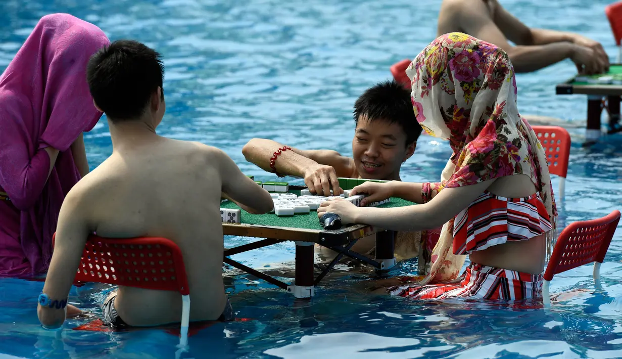 Pengunjung bermain mahjong di dalam kolam renang di wilayah Chongqing, Tiongkok, Rabu (2/8). Pemerintah setempat telah mengeluarkan peringatan merah terkait cuaca panas dengan suhu di beberapa daerah hampir mencapai 40 derajat celcius. (STR / AFP)