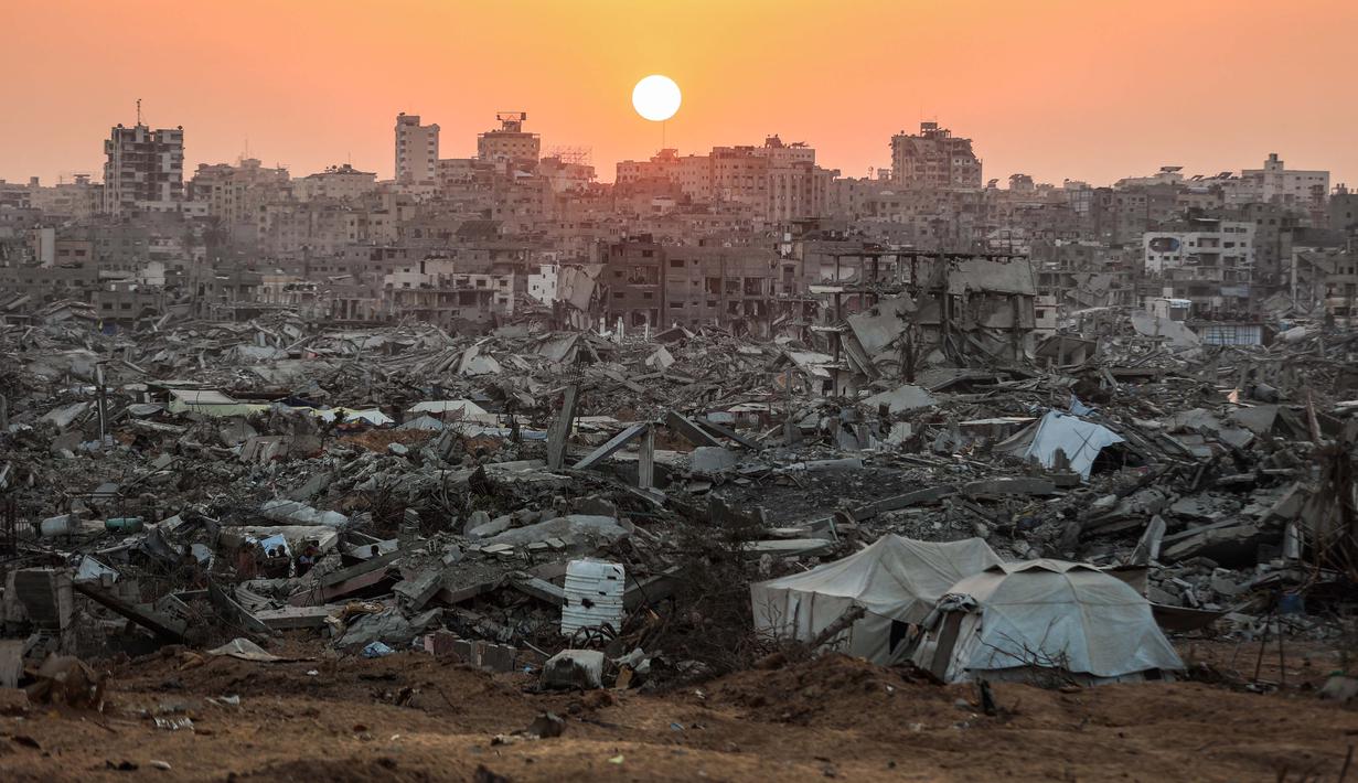 Farhan Haq menambahkan, layanan kemanusiaan di Gaza masih berada di bawah tekanan berat akibat pengungsian massal, kerusakan infrastruktur, dan situasi keamanan yang tidak stabil, terutama di wilayah utara. Tampak dalam foto, matahari terbenam di atas kawasan Jabalia yang rusak parah di bagian utara Jalur Gaza pada Jumat 7 November 2025. (Omar AL-QATTAA/AFP)