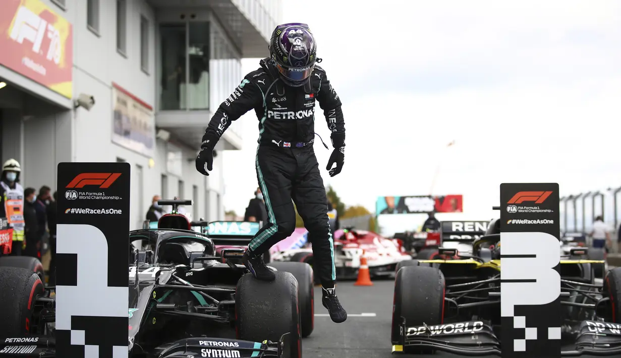 Pembalap Mercedes Lewis Hamilton melompat dari mobilnya setelah memenangkan F1 GP Eifel di Nuerburgring, Nuerburg, Jerman, Minggu (11/10/2020). Hamilton dengan 91 kemenangannya menyamai legenda F1 Michael Schumacher. (Bryn Lennon, Pool via AP)