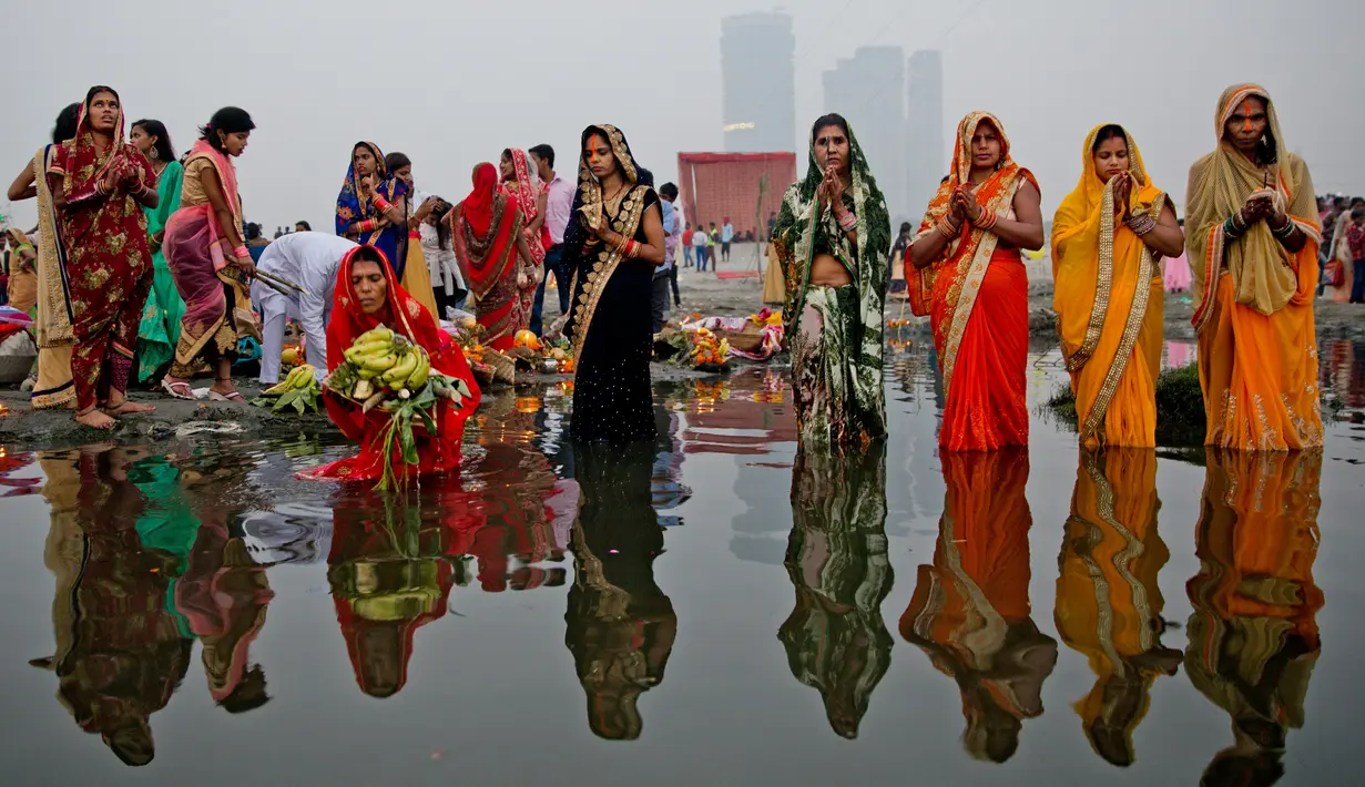 Umat Hindu India berdoa sambil berdiri di perairan Sungai Yamuna selama Festival Chhath di New Delhi, Selasa (13/11). Festival Hindu kuno ini dilakukan sebagai bentuk terima kasih kepada Dewa Matahari yang menopang kehidupan di bumi. (AP/Altaf Qadri)