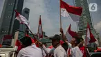 Sejumlah warga yang melintas mengibar-ngibarkan bendera Merah Putih saat melintasi kawasan Bundaran Hotel Indonesia, Jakarta, Sabtu (17/8/2024). (Liputan6.com/Angga Yuniar)