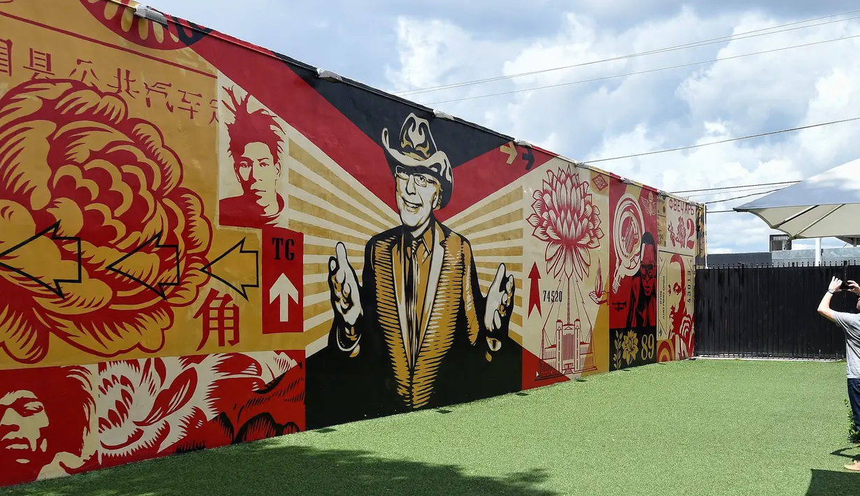 Pengunjung mengambil gambar mural yang dibuat oleh seniman Shepard Fairey di kawasan Wynwood, Miami, Florida pada 28 September 2016. Goldman Properties menggelar pameran mural untuk merevitalisasi lingkungan. (AFP PHOTO / Rhona WISE)