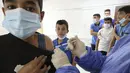 Pegawai Kementerian Kesehatan Palestina memberikan suntikan vaksin COVID-19 Pfizer/BioNTech kepada siswa sekolah berusia 12 tahun ke atas di Desa Dura, Hebron, Palestina, 24 November 2021. Total kasus COVID-19 di Palestina mencapai 428.857, meninggal 4.520, sembuh 421.669. (HAZEM BADER/AFP)