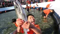 Seorang anak bergembira saat mendapatkan ikan selama lomba memancing ikan trout di sungai yang membeku di Hwacheon, Korea Selatan (6/1). (AP Photo/Ahn Young-joon)