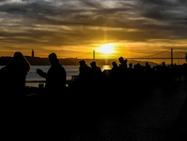 Orang-orang menikmati matahari terbenam di Ribeira das Naus di Lisbon (17/12). Lisboa atau Lisbon merupakan ibu kota  Portugal. (AFP Photo/Patricia De Melo Moreira)