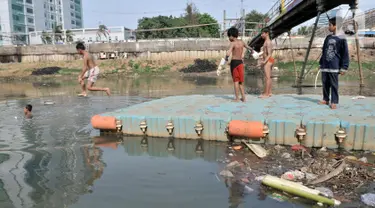 Anak-anak berenang di Kanal Banjir Barat, Jakarta, Minggu (3/11/2019). Banyaknya sampah yang menggenang tidak menghentikan keseruan anak-anak berenang di Kanal Banjir Barat. (merdeka.com/Iqbal Nugroho)