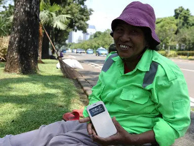 Sambil tersenyum, Ibu Tuti menunjukan ponsel baru miliknya hasil pemberian Gubernur DKI Jakarta, (24/3). Wanita 54 tahun ini mendapatkan hadiah ponsel karena aksinya yang berani memarahi pendemo perusak Balai Kota. (Liputan6.com/Yoppy Renato)